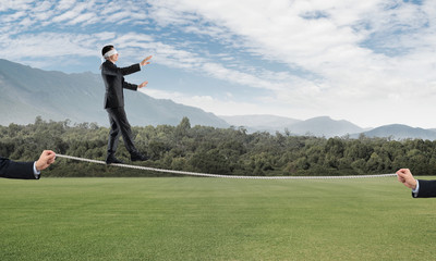 Business concept of risk support and assistance with man balancing on rope