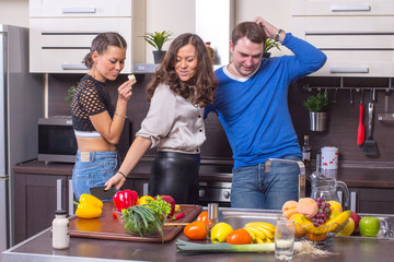 Smiling people with smartphone cooking vegetables at home