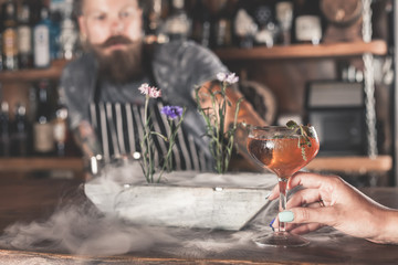 Beautiful girl is drinking a cocktail with ice vapor in the bar