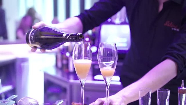the bartender pours champagne into glasses, slow motion