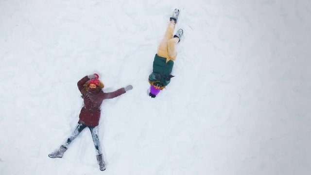 Young girls do a snow angel on a sunny winter day. Slow motion. 4K.