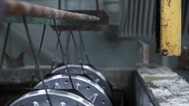 factory. production. metal parts lifted from industrial tubs with water. galvanization