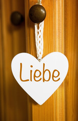 white heart hanging on door knob with german word for Love