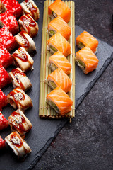 Japanese cuisine. Sushi roll with fresh ingredients on a stone plate and background.