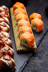 Japanese cuisine. Sushi roll with fresh ingredients on a stone plate and background.
