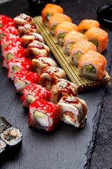 Japanese cuisine. Sushi roll with fresh ingredients on a stone plate and background.