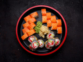 Japanese cuisine. Sushi roll with fresh ingredients on a round wooden plate and stone background.