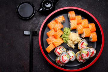 Japanese cuisine. Sushi roll with fresh ingredients on a round wooden plate and stone background.