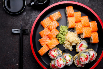 Japanese cuisine. Sushi roll with fresh ingredients on a round wooden plate and stone background.