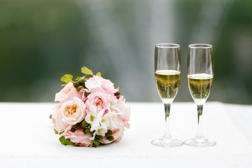 Two glasses of champagne on the background of the wedding bouquet of roses