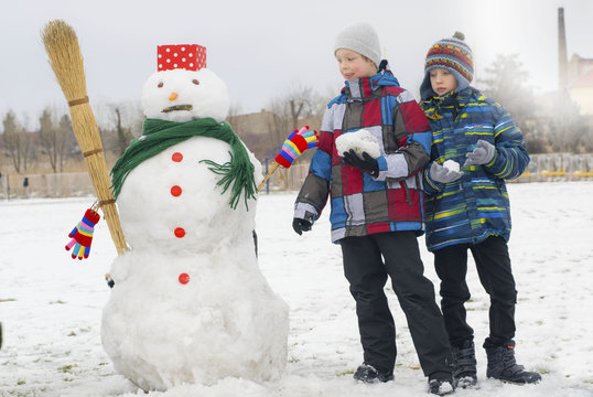 Two boys making a snowmen