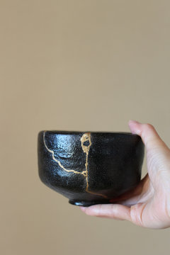 金継された抹茶の茶碗を女性が右手で持つ　ぼかし背景