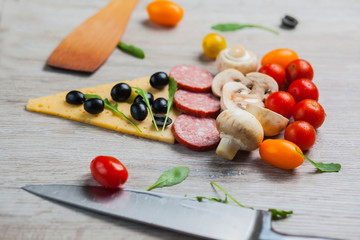 Creative composition of ingredients tomatoes, cheese, salami, mushrooms, arugula, olives in the form of a slice of pizza