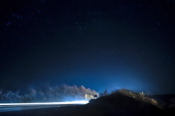 Beautiful stars on night sky near road with car light tracks