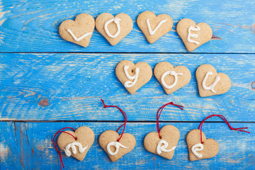 Homemade heart shape cookies on blue background, words LOVE YOU