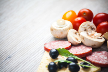 Creative composition of ingredients tomatoes, cheese, salami, mushrooms, arugula, olives in the form of a slice of pizza