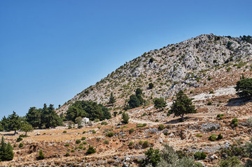 Fototapeta na wymiar Orthodox chapel on a rocky slope on the island of Kos in Greece.