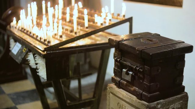 donation box near burning candles in a church