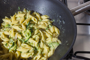 Zucchini pasta that has cook at home on a skillet over a gas stove.