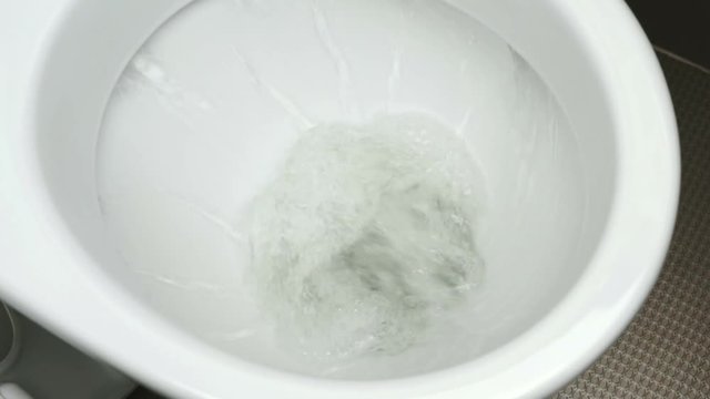 Close up view of flushing white toilet. Cleaning of the toilet bowl using the water stream