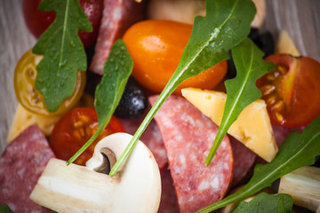 Creative composition of ingredients tomatoes, cheese, salami, mushrooms, arugula, olives in the form of a slice of pizza