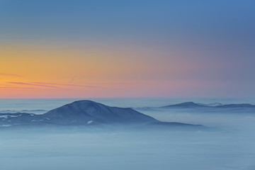 Fototapeta na wymiar Majestic winter view with sunset over the misty valleys of the Carpathians mountains, Transylvania region, Romania.