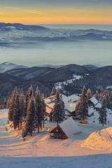 Snowy Postavaru chalet in the warm sunset light, at 1604m altitude in Postavaru mountain, Poiana Brasov winter resort, Brasov county, Romania.