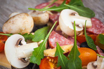 Creative composition of ingredients tomatoes, cheese, salami, mushrooms, arugula, olives in the form of a slice of pizza