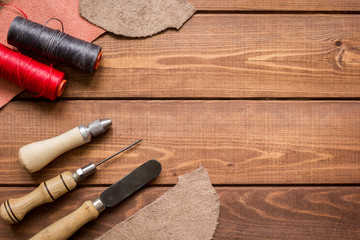 leather craft instruments on wooden background top view