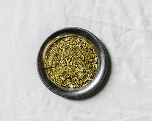 Yerba mate tea in on a metal plate against white background