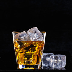 Glass of scotch whiskey and ice over black background.