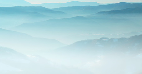 Mountain layer in morning sun ray and winter fog