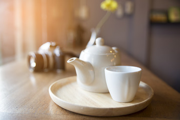 In the cafe,have a cup of coffee, teapot and old camera placed on a wooden table.