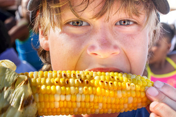 Happy boy eating corn on the cob © soupstock