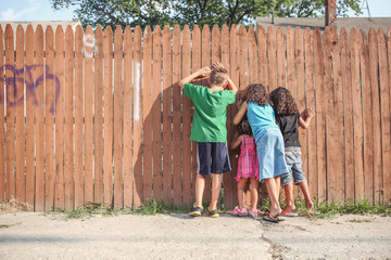 Kids peeking through a fence