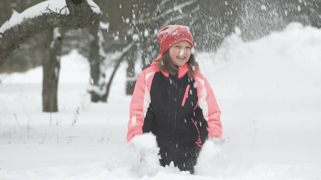 Slow motion of joyful child playing in snow. Happy girl having fun outside winter day