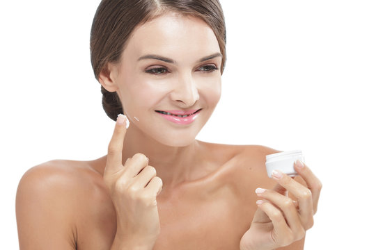 beautiful woman applying some facial cream while smiling