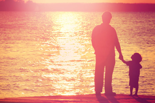 Father And Son  On A Dock At Sunset, Boy Looking Up At His Fathe