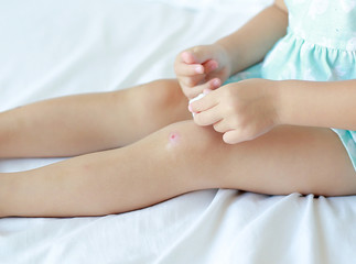 Fototapeta na wymiar Close Up of child girl dressing wound on knee by self on the bed.