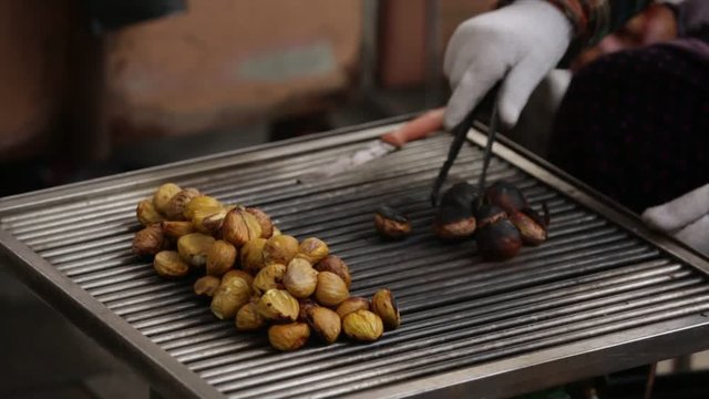 Man roasts chestnuts grilled on a city street.