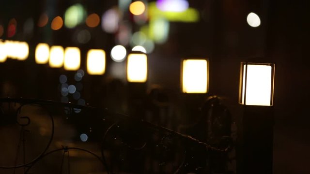 Lanterns outside street cafe at night. In the background traffic. Focus moves from front to back.