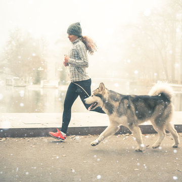 Image of young girl running with her dog, alaskan malamute