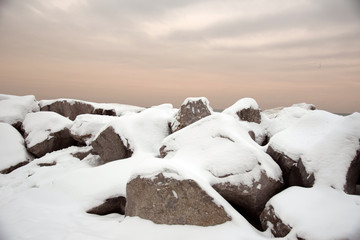 snow covered rocks along shore of Lake Michigan under pink sky