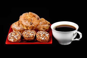 Cup of coffee, muffins and chocolate chip cookies in a red plate on a black background