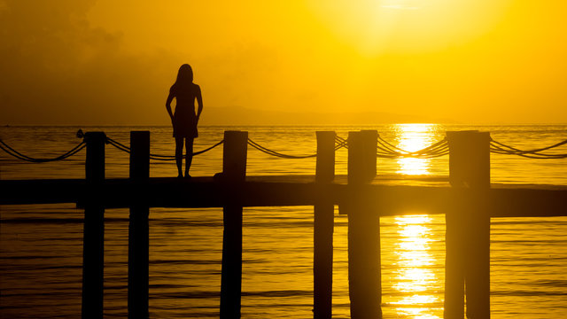 Woman Standing On A Fishing Dock With Golden Island Sunset - Silhouette In Siargao, Philippines