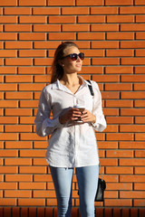 Woman in sunglasses near brick wall