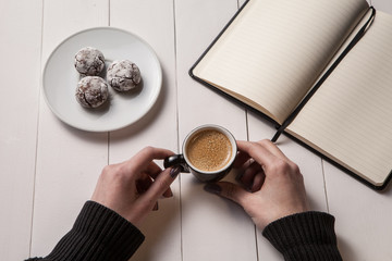 cup of coffee in hand at the girl, biscuits on a plate.