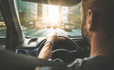 Männlicher Autofahrer in der Großstadt (Rückansicht) mit Gegenlicht
