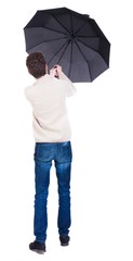 Back view of man in jeans under an umbrella. Standing young guy. Rear view people collection.  backside view of person.  Isolated over white background. The guy is trying to keep the wind break-out