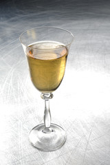 White wine in a glass on a metal / silver / light background 